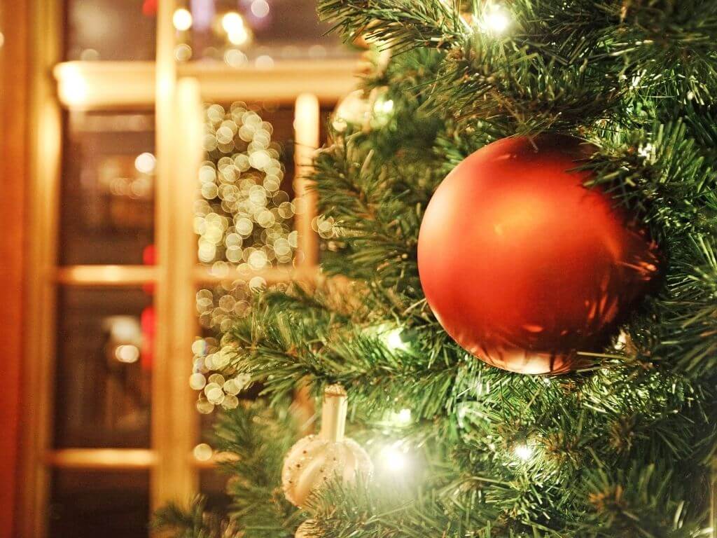 A close up of a Christmas tree with a red bauble decoraiton