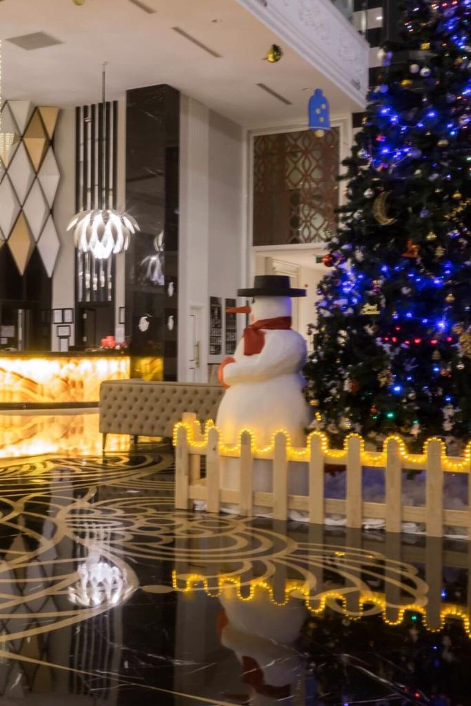 A snowman and Christmas tree with blue lights in a hotel lobby