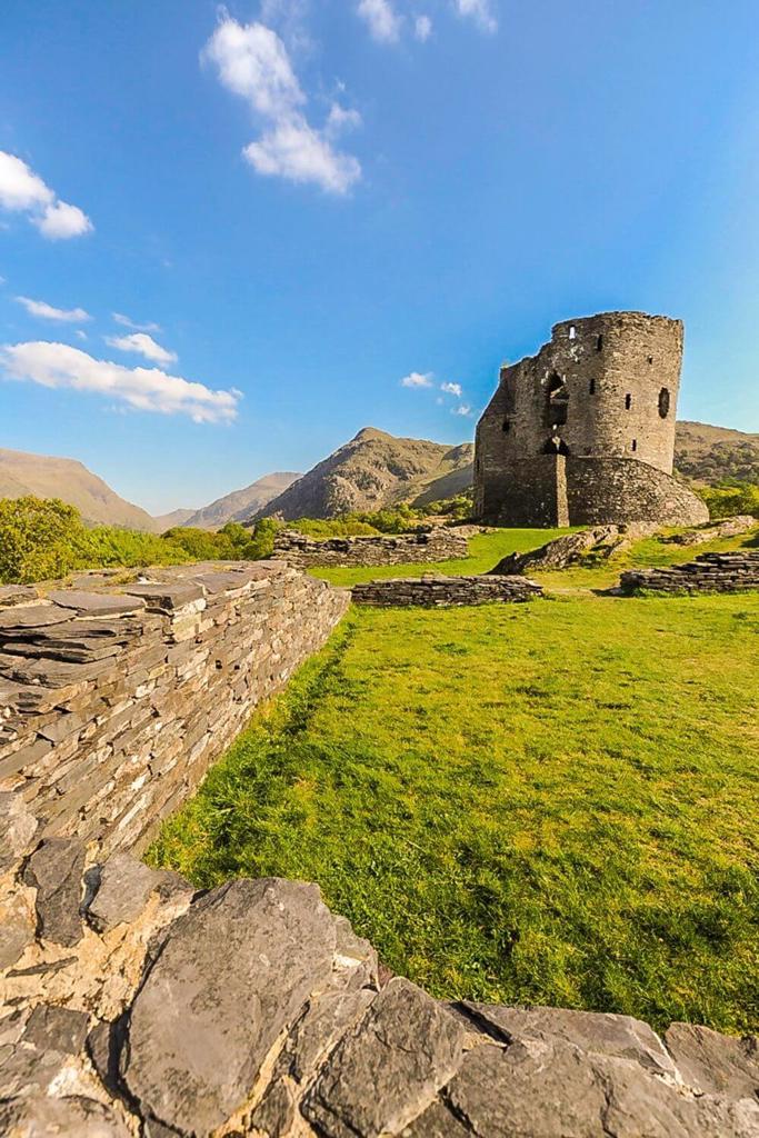 Dolbadarn Castle with blue skies overhead and lush green grass in the foreground